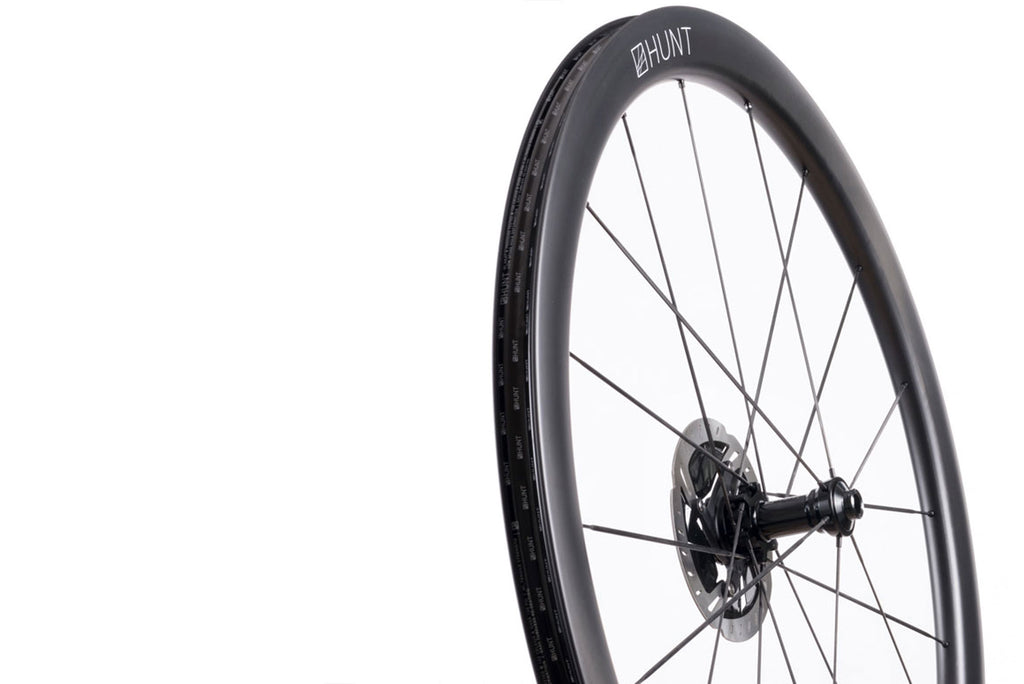 Up close image of the HUNT 44 UD Carbon Spoke Disc front wheel, showing the detailed rim and hub design